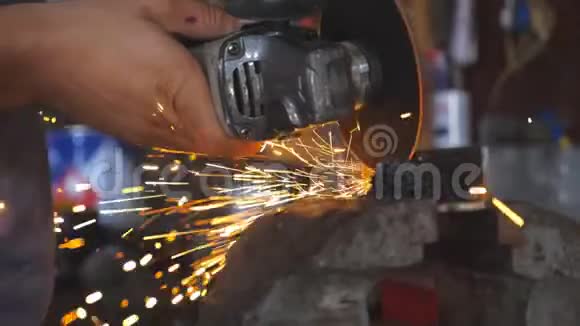 在车间用电动砂轮将成年焊工切割钢的男性手闭上专业武器视频的预览图