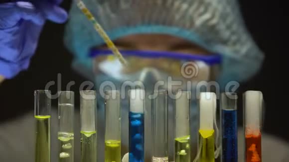 在黑暗实验室用蓝色液体测量试管中酸度水平的科学家视频的预览图