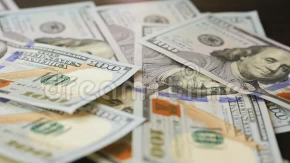 一百美元的钞票凌乱地落在桌子上视频的预览图