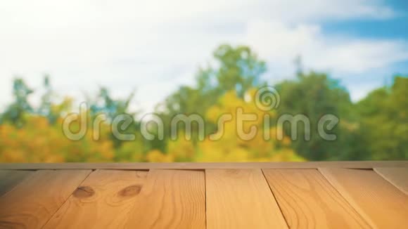 木制的桌面上五颜六色模糊的秋天背景与蓝天和黄色的树木衬托视频的预览图