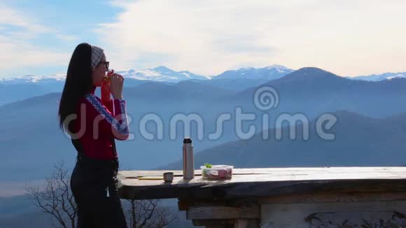 女人吃三明治喝茶以抵御山岳景观视频的预览图