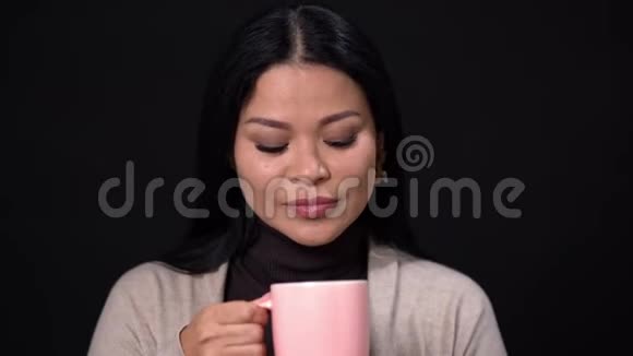 一个黑人背景下的布鲁内特女人正在喝一杯粉红色的咖啡视频的预览图