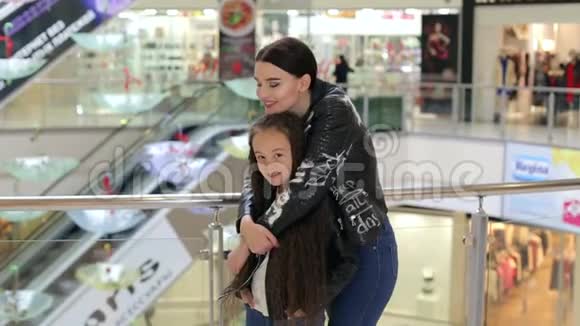 快乐的妈妈穿着皮夹克在一个大型购物中心拥抱她的女儿视频的预览图