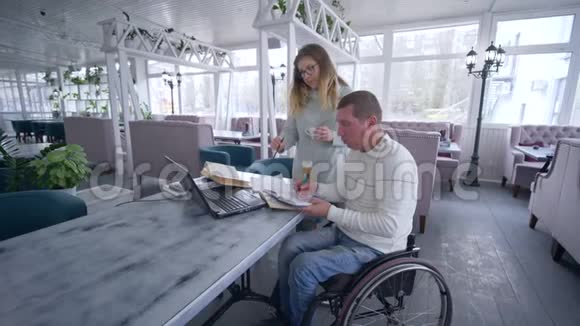 餐厅经理残疾人轮椅上的男子在工作时与女性讨论规划和发展商业想法视频的预览图