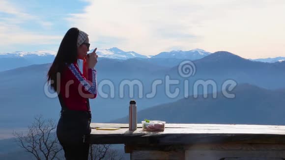 女人吃三明治喝茶以抵御山岳景观视频的预览图