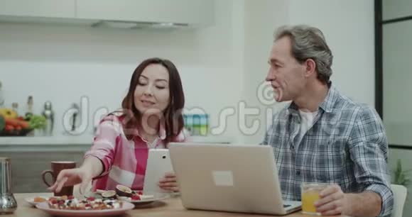 在厨房一起吃早餐成熟的夫妇吃健康的食物妻子给丈夫尝试新的食谱他视频的预览图