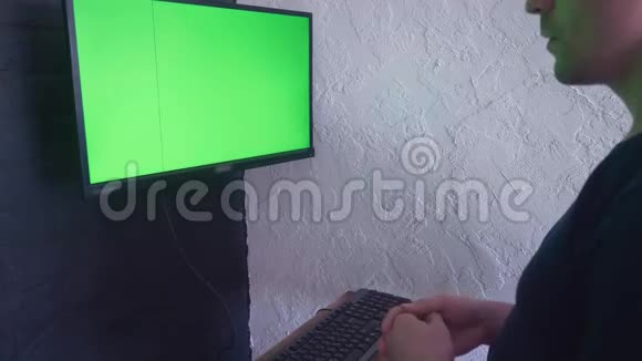 年轻人正在用一个绿色屏幕模拟电脑工作4K用两个手指在键盘上打字视频的预览图