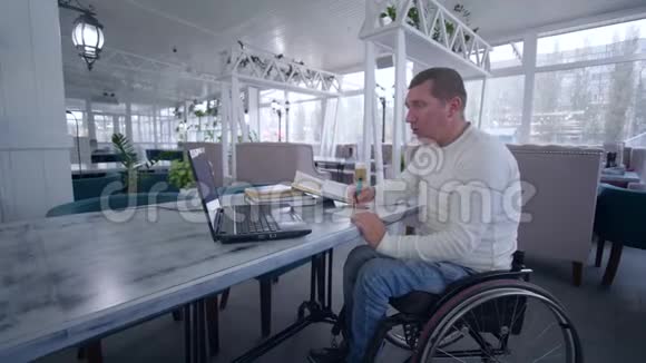 轮椅上的残疾学生利用手提电脑进行视频教育从网上教学中学习做笔记视频的预览图