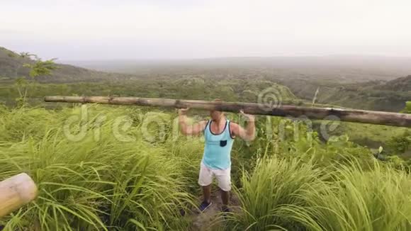 运动员举起沉重的木棒在热带山和高地景观健美运动员训练新闻练习视频的预览图