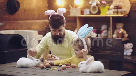 爸爸和儿子画了复活节彩蛋和复活节兔子玩为复活节做准备的幸福家庭可爱的小男孩视频的预览图