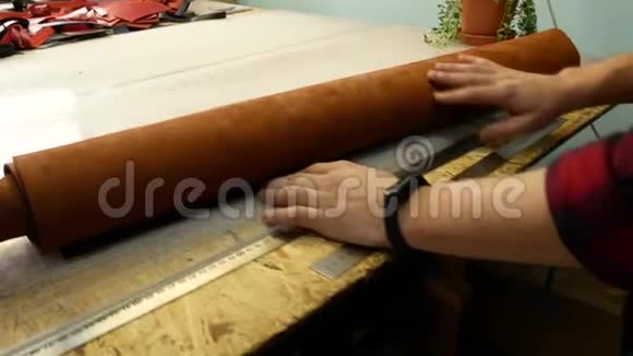一个剥皮者在桌子上展开一卷皮革皮革大师选择扭曲的皮革关门视频的预览图
