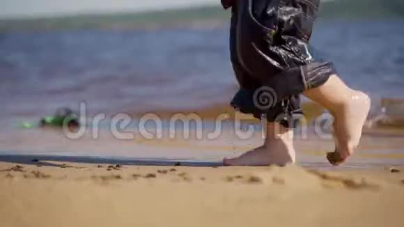 一个穿着湿裤子的孩子正沿着沙滩散步双脚合拢视频的预览图