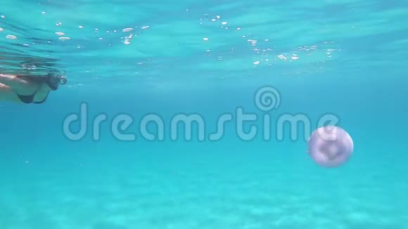 一位年轻美丽的女子在水下慢动作游泳时她穿着透明的蓝色游泳身上有根瘤俗称视频的预览图