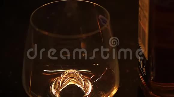 波旁酒白兰地或威士忌的微光镜头倒在黑桌上的酒杯里视频的预览图