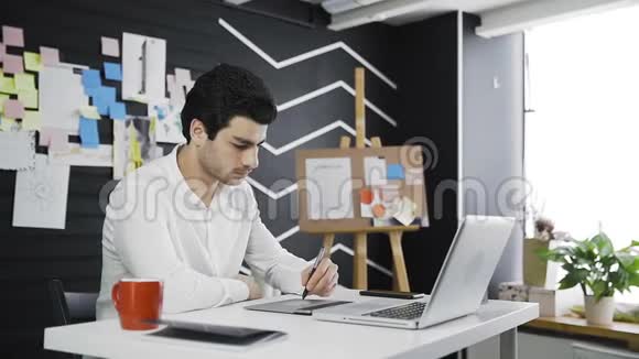 休闲男性设计师喝咖啡和使用图形平板电脑视频的预览图
