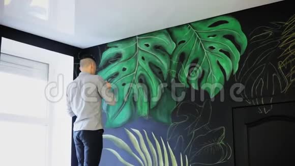 在墙上画画用画笔涂鸦艺术家画绿色的树枝视频的预览图