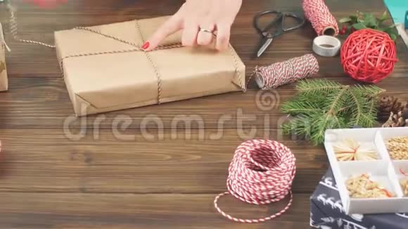 女性手在黑色木制背景下用手工生态纸包装圣诞礼物视频的预览图