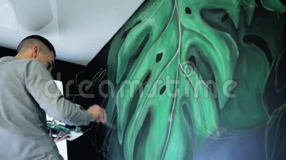 涂鸦艺术家在天花板下的墙上画油漆用刷子的男性手艺术观念视频的预览图