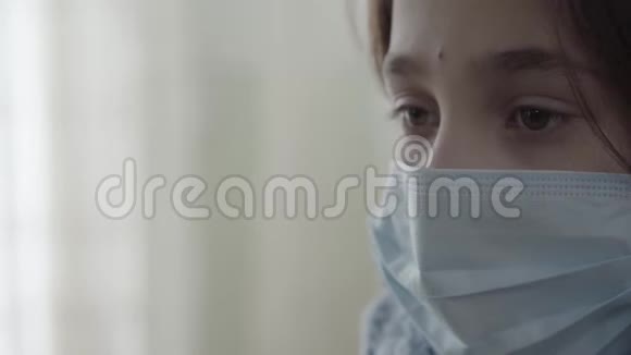 特写肖像悲伤生病的女孩脸上戴着无菌面具低头看着家生病孩子的概念医药视频的预览图