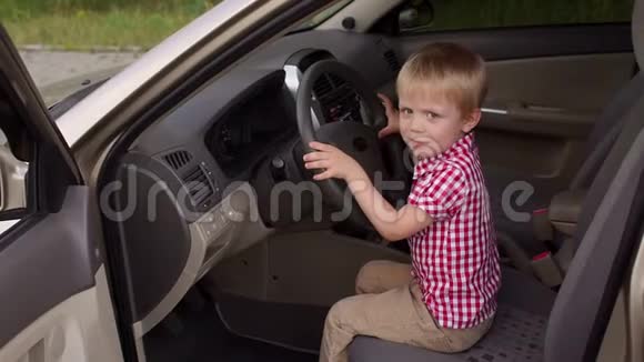小男孩坐在驾驶座轮子后面他玩转轮子视频的预览图