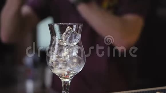 酒吧里摆着一个装满冰块的鸡尾酒杯酒保把液体混合在摇瓶里视频的预览图