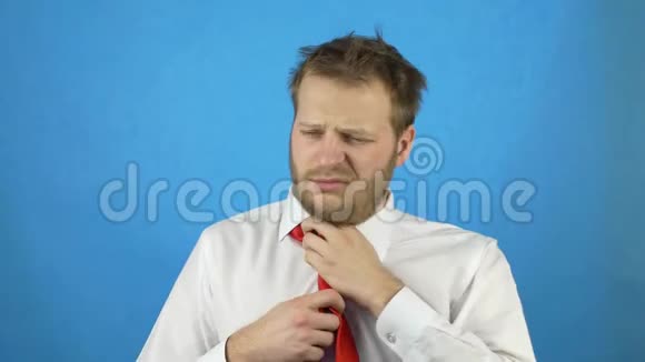 年轻的醉白种人穿着白衬衫带着一条宿醉领带蓝色背景视频的预览图