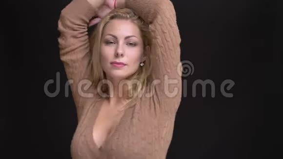 美丽的白种人长发女子的肖像慢慢地摆在黑色背景上的镜头中视频的预览图