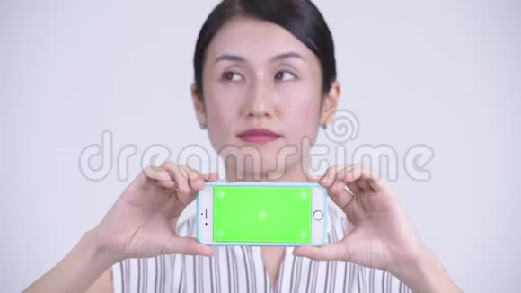 一位快乐美丽的亚洲女商人一边看手机一边思考视频的预览图