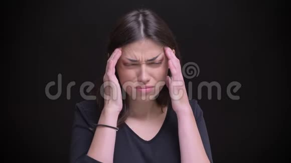 年轻的白种人长发黑发女孩在黑色背景下做按摩和头痛的肖像视频的预览图