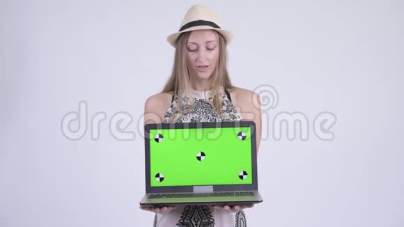 一幅快乐的金发女游客在展示笔记本电脑时思考的肖像视频的预览图