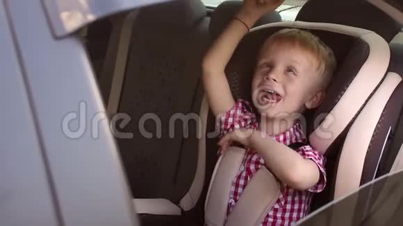 一个快乐的婴儿坐在儿童的汽车座位上挥舞着手视频的预览图