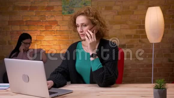 一位年轻的女商人在笔记本电脑上工作打电话在办公室里放松视频的预览图