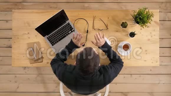 英俊的年轻商人坐在办公桌前拿着笔记本电脑和别人说话视频的预览图