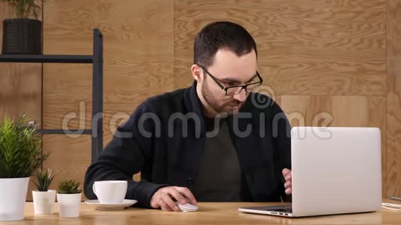 感觉很累沮丧的年轻英俊男子坐在他的工作场所背着他神情疲惫视频的预览图