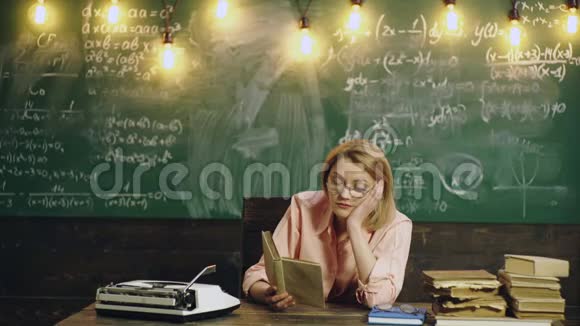 女人在学校教室里的绿色黑板背景上读一本书教室里的老师学习概念视频的预览图