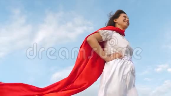 美丽的女孩梦想成为超级英雄性感的超级英雄女孩穿着红色斗篷站在田野上斗篷飘扬着视频的预览图