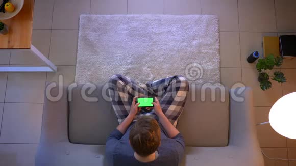 在舒适的家中年轻的穿着随意的男性在电话中与绿色屏幕聊天的特写镜头视频的预览图