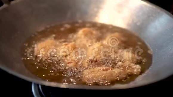 在金属炒锅里热沸油的炸鸡的近景视频的预览图