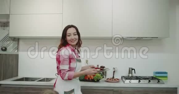 成熟的女人在早晨为她的家人做饭然后把食物放在餐桌上快乐视频的预览图