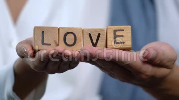 在幸福的夫妻手中的木立方体上爱字信任和支持关系视频的预览图
