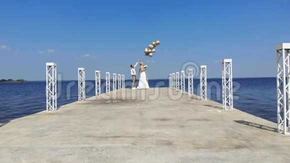 空中视频美丽的新婚夫妇新娘和新郎在户外跳舞在一个美丽的码头在蔚蓝的大海和视频的预览图