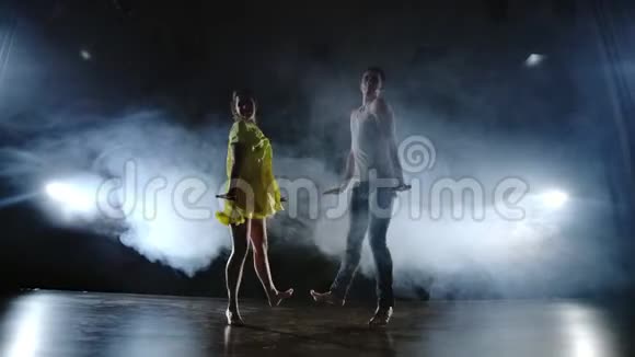 一个男人和一个女人一起跳舞一个穿着牛仔裤的滑稽舞蹈和一条黄色的裙子在舞台上冒烟音乐剧视频的预览图
