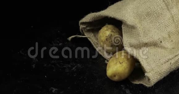 土豆从帆布袋落在黑色的冲浪板上一堆新鲜的生薯视频的预览图