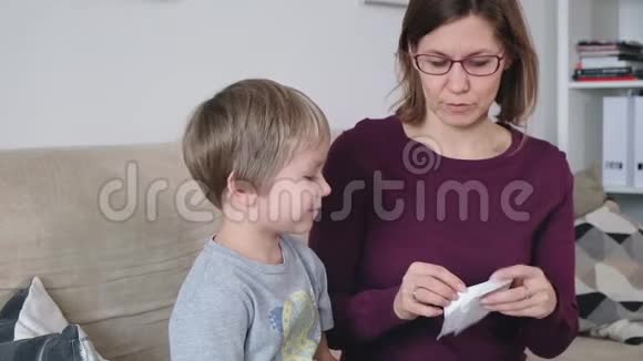 妈妈和小男孩流鼻涕妈妈照顾她生病的蹒跚学步的男孩视频的预览图