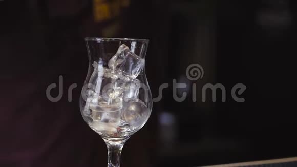 调酒师用手将调酒器杯中的混合物倒入杯子中的冰块中这是一种鸡尾酒视频的预览图