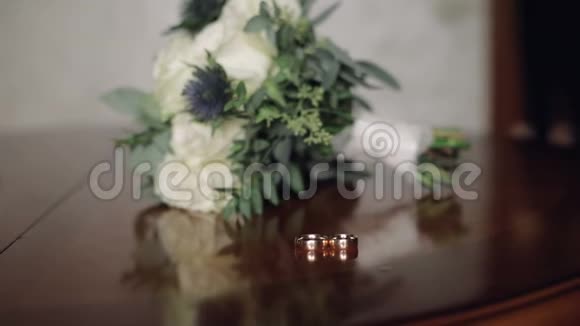 新郎手拿着一束婚礼花束放在结婚戒指旁边的桌子上视频的预览图
