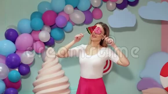 一个穿着亮衣服带棒棒糖的女孩她用大棒棒糖遮住眼睛视频的预览图