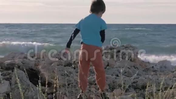 在石岸穿脏衣服的孤儿小难民男孩在海上玩耍概念移徙和生活方式视频的预览图
