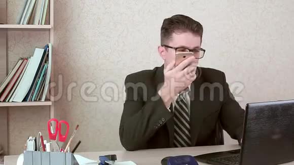 男性办公室经理一个语音信息到智能手机他在他的笔记本上工作视频的预览图