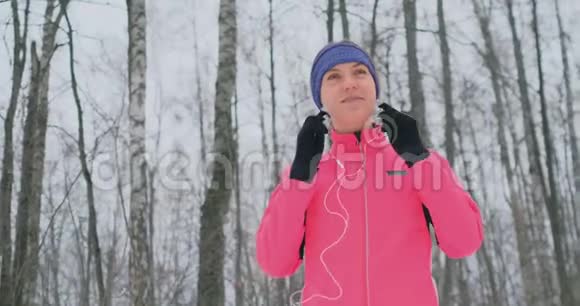 晨冬慢跑前的女孩把耳机插在耳朵里准备穿过自然公园视频的预览图